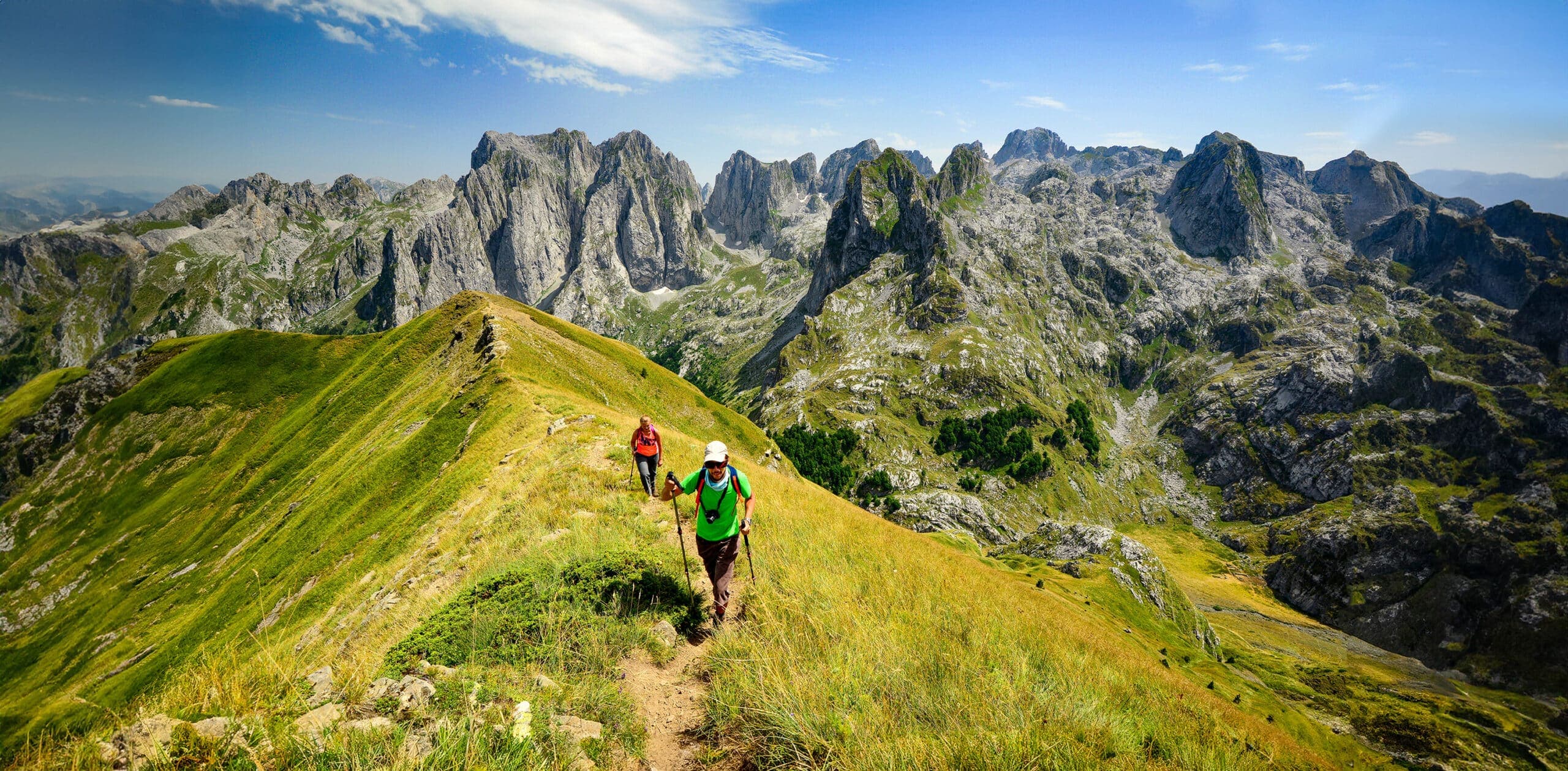 Hikers climbing a ridgeline trail toward the Peaks of the Balkans